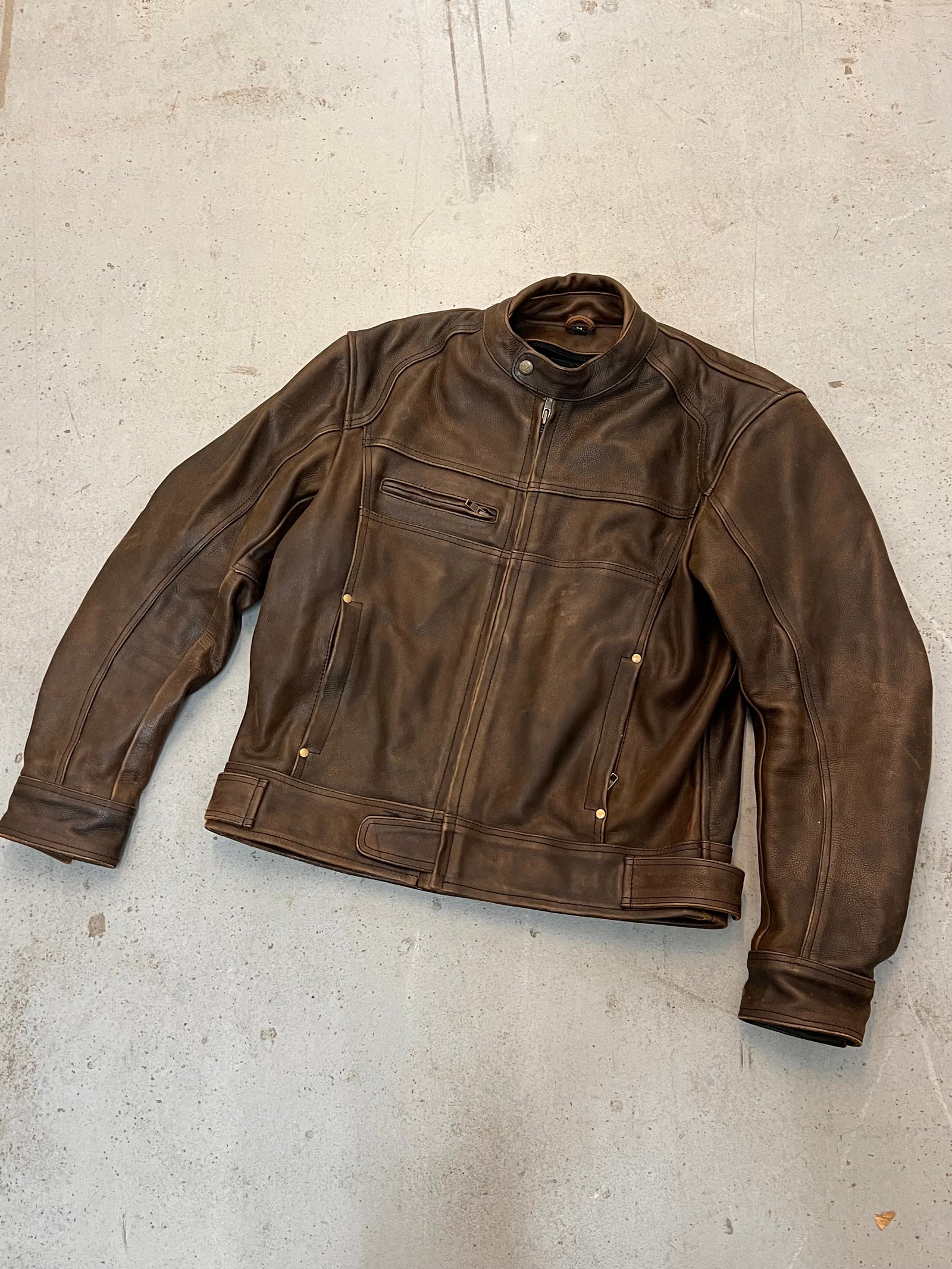 Brown leather motor jacket on a concrete floor.