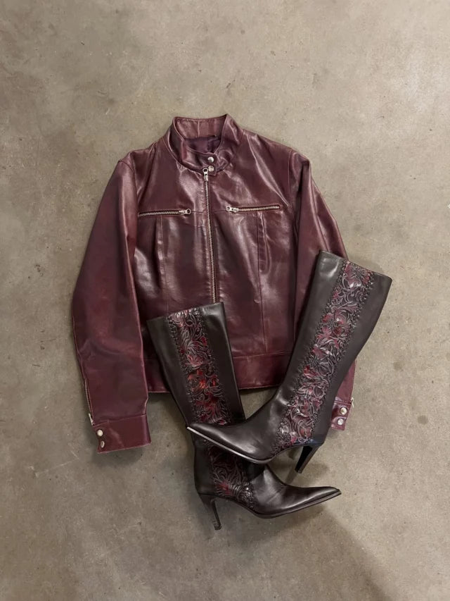 Oxblood jacket and embroidered boots arranged on a concrete floor.