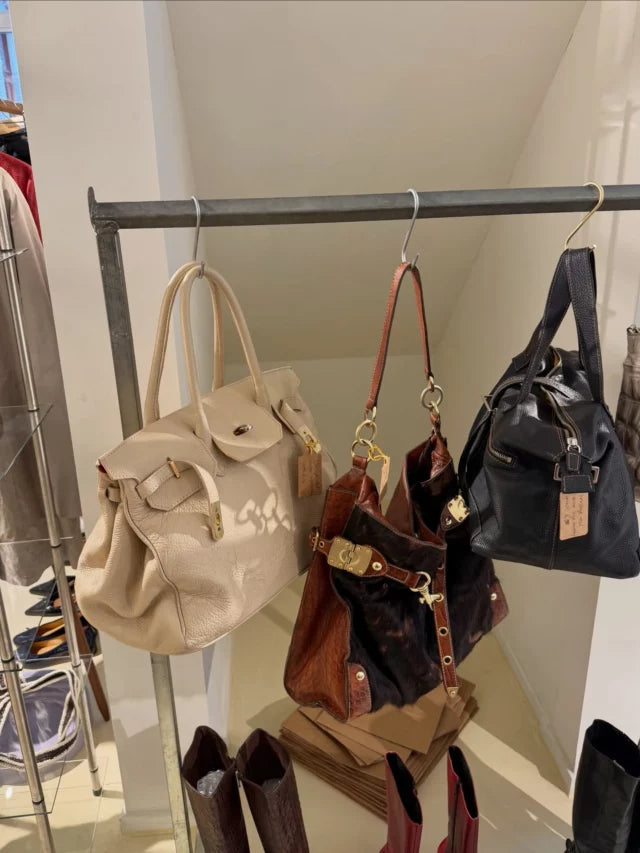 A selection of neutral, oxblood and black bags displayed on a metal rail.