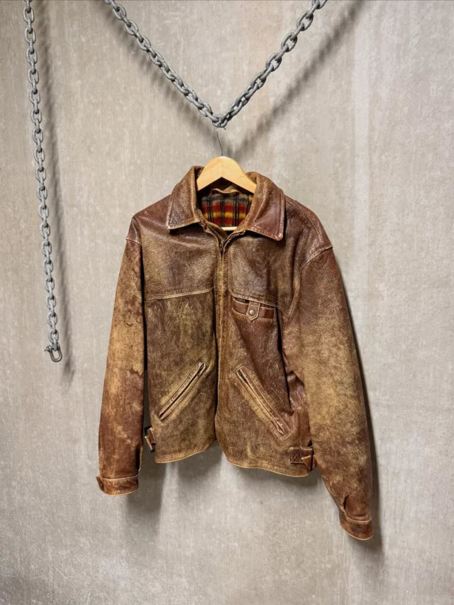 Distressed brown jacket displayed against concrete and dark chain details.