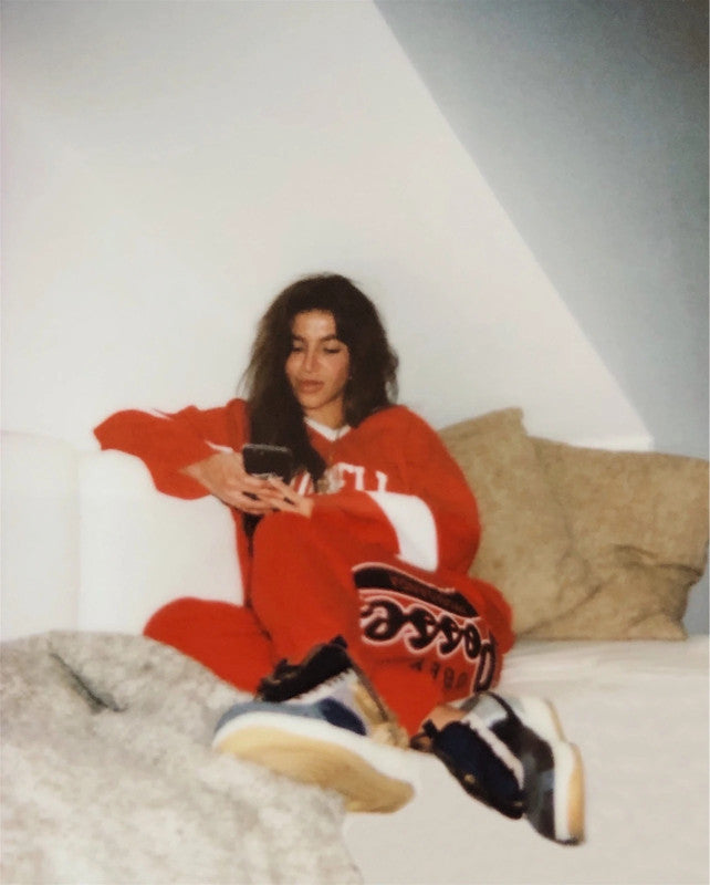 Rochell, founder of Ronnies Vintage, sitting on a sofa in a red outfit